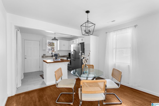 dining space with an inviting chandelier, sink, and light hardwood / wood-style floors