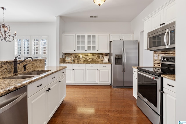 kitchen featuring sink, white cabinetry, stainless steel appliances, light stone countertops, and decorative light fixtures