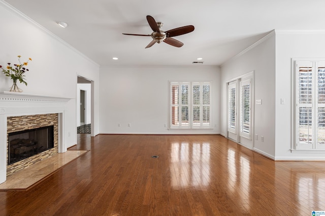 unfurnished living room with hardwood / wood-style flooring, a stone fireplace, ornamental molding, and ceiling fan