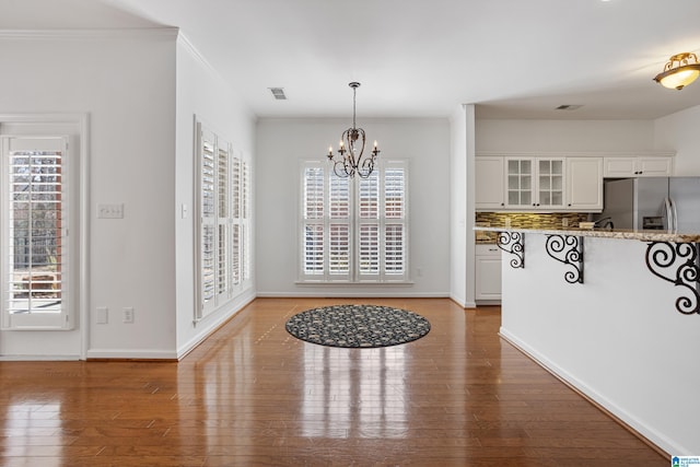 interior space with an inviting chandelier, hardwood / wood-style flooring, and crown molding