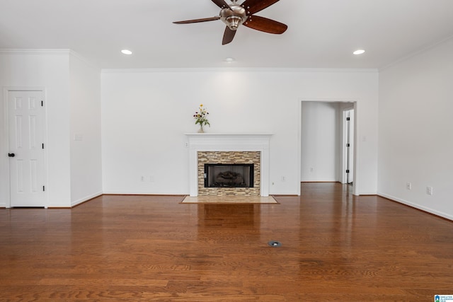 unfurnished living room featuring a stone fireplace, dark wood-type flooring, ornamental molding, and ceiling fan