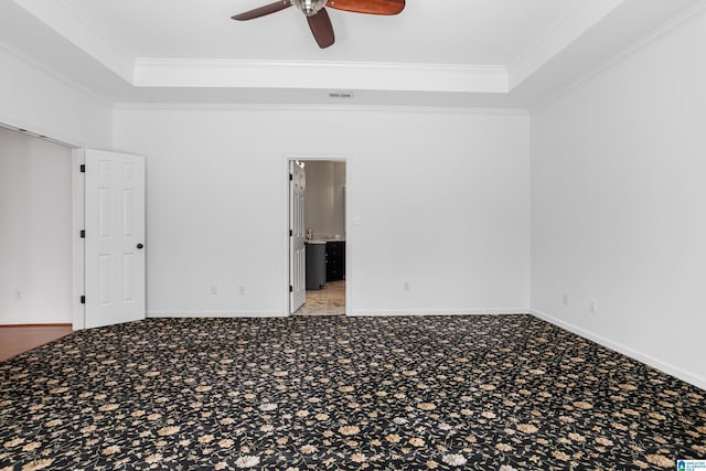 carpeted spare room featuring ceiling fan, ornamental molding, and a tray ceiling