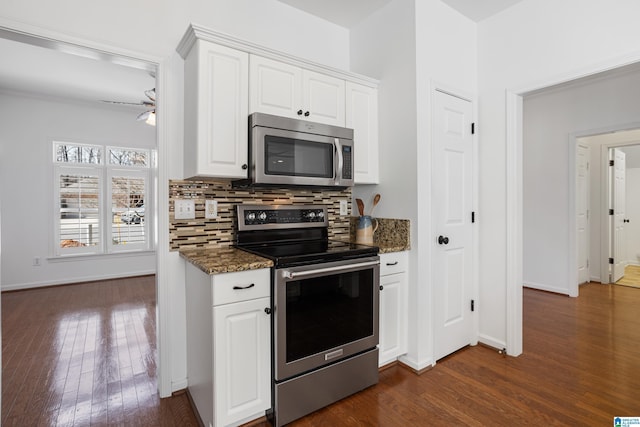 kitchen featuring appliances with stainless steel finishes, tasteful backsplash, dark stone countertops, white cabinets, and dark hardwood / wood-style flooring