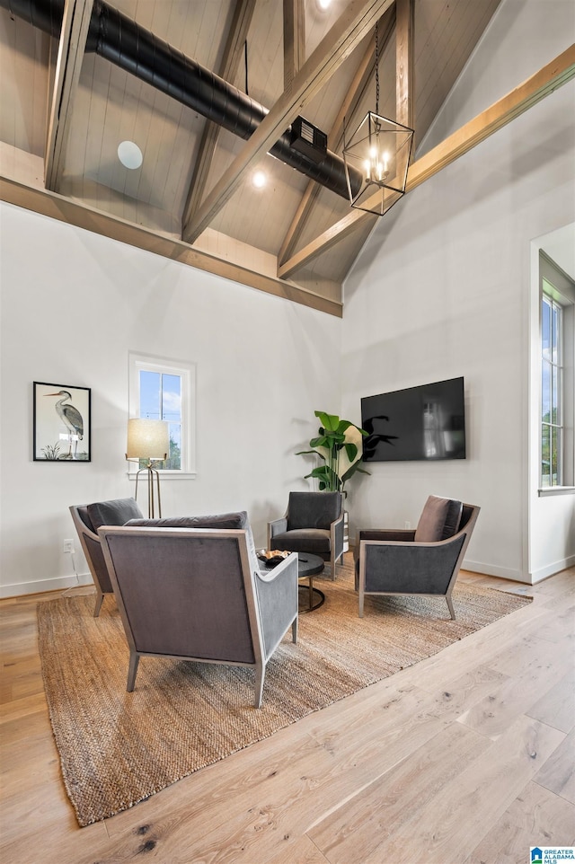 living room featuring beam ceiling, plenty of natural light, high vaulted ceiling, and light wood-type flooring