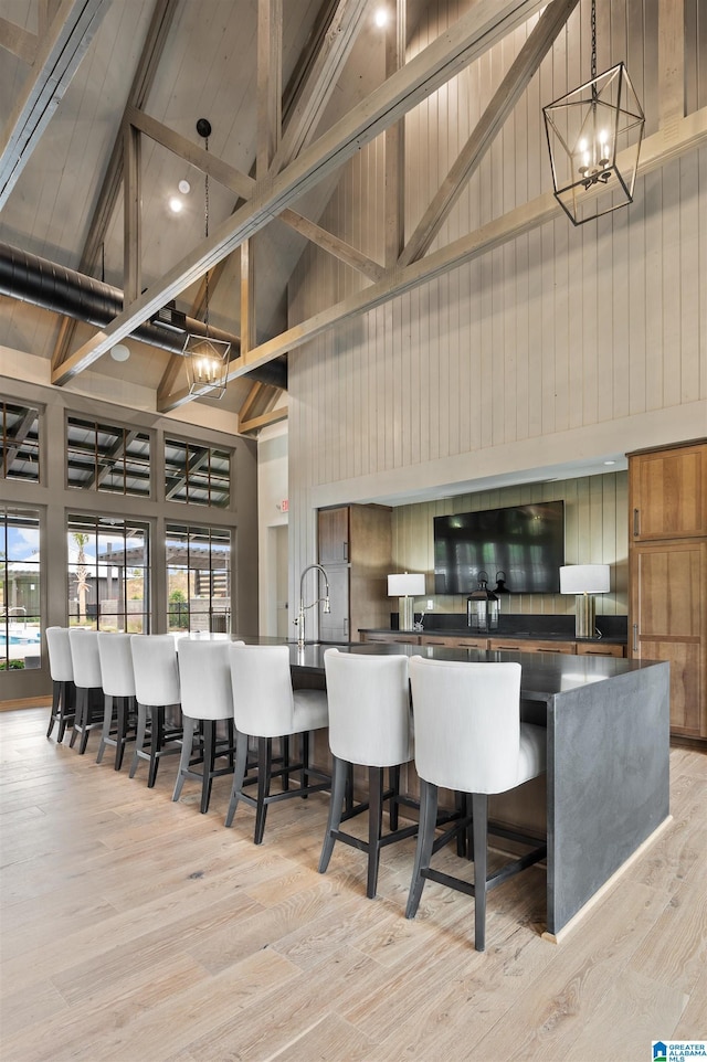 kitchen featuring high vaulted ceiling, a breakfast bar, a notable chandelier, and light hardwood / wood-style floors