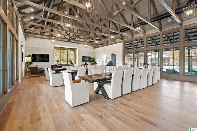 dining space featuring beam ceiling, light hardwood / wood-style flooring, and high vaulted ceiling