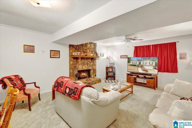 carpeted living room with ceiling fan, a stone fireplace, ornamental molding, and a textured ceiling