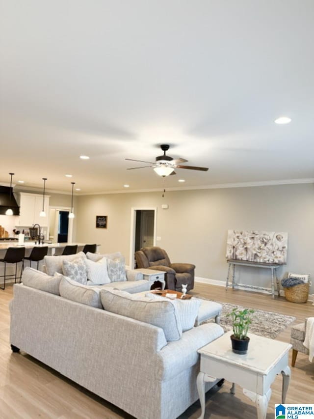 living room with ornamental molding, sink, ceiling fan, and light hardwood / wood-style floors