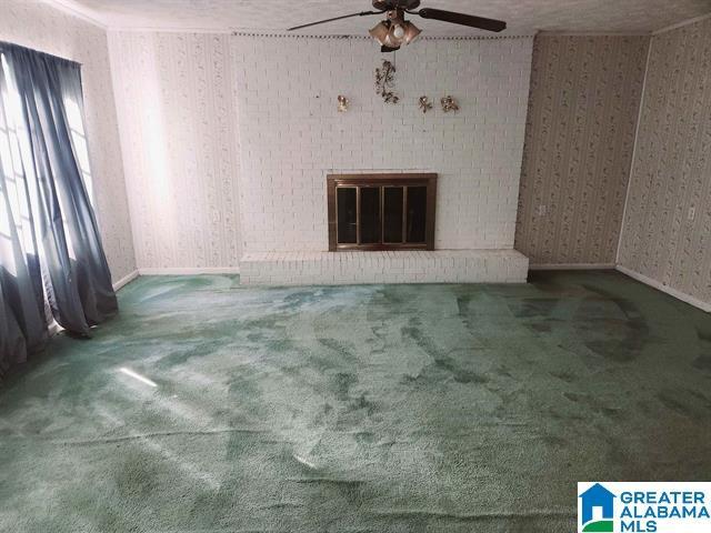 unfurnished living room featuring ceiling fan, a fireplace, and carpet flooring