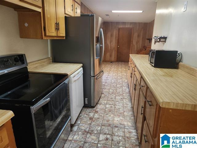 kitchen featuring white dishwasher, electric range, and wood walls