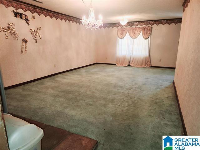 unfurnished room with a notable chandelier, crown molding, and carpet floors