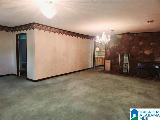 unfurnished living room with carpet floors, a textured ceiling, and a chandelier