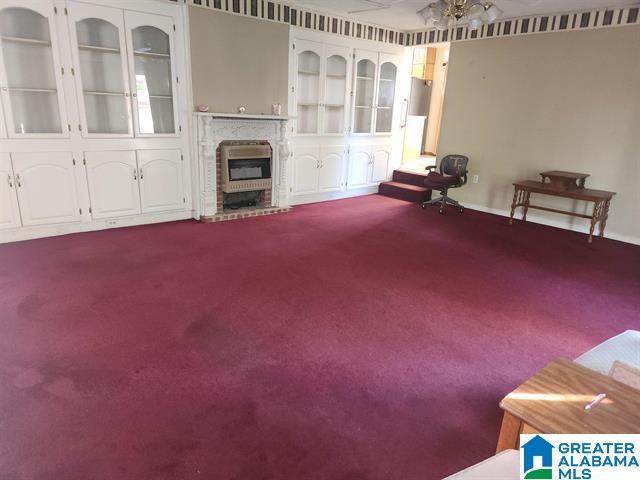 unfurnished living room featuring carpet flooring, heating unit, ceiling fan, and built in shelves