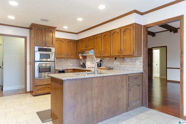 kitchen featuring light stone counters, double oven, backsplash, and kitchen peninsula