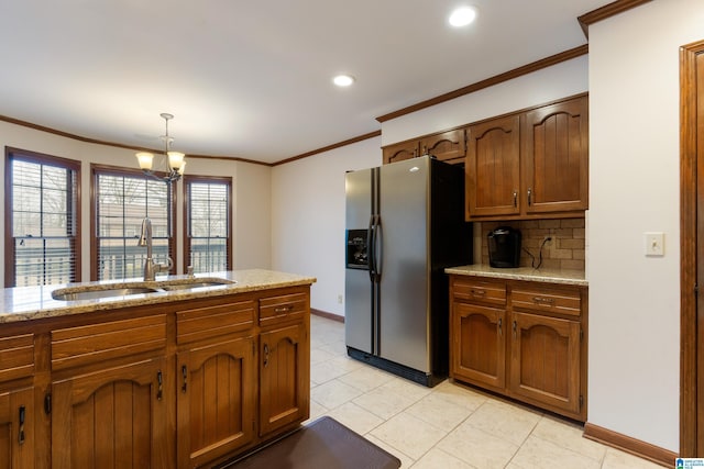 kitchen with sink, hanging light fixtures, stainless steel refrigerator with ice dispenser, tasteful backsplash, and ornamental molding