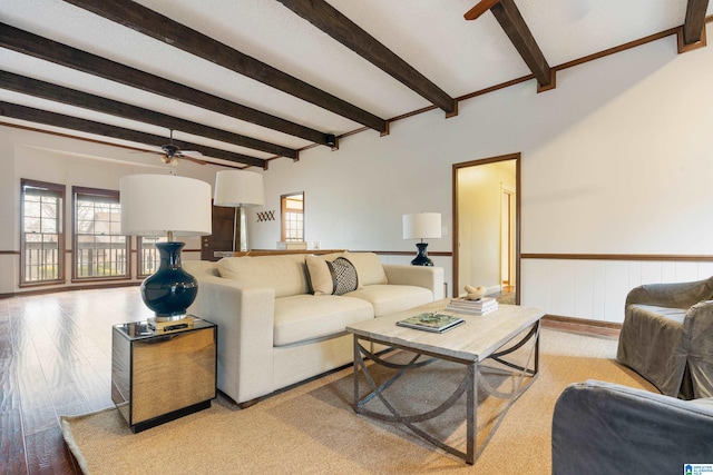 living room with beamed ceiling, ceiling fan, and light wood-type flooring