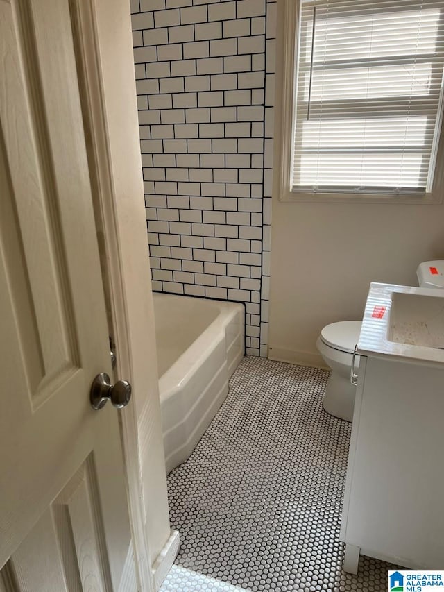 full bathroom featuring tile patterned flooring, vanity, tiled shower / bath combo, and toilet