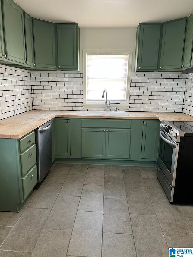 kitchen with wood counters, appliances with stainless steel finishes, green cabinets, and sink