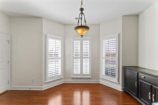 unfurnished dining area with dark wood-type flooring