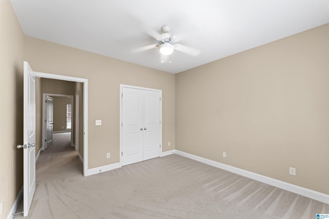 unfurnished bedroom featuring ceiling fan, light colored carpet, and a closet