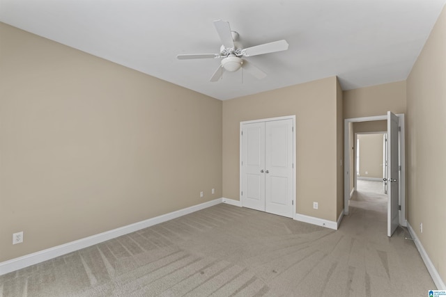 unfurnished bedroom featuring ceiling fan, a closet, and light carpet