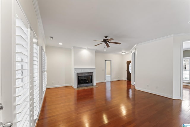 unfurnished living room with a tiled fireplace, hardwood / wood-style floors, crown molding, and ceiling fan