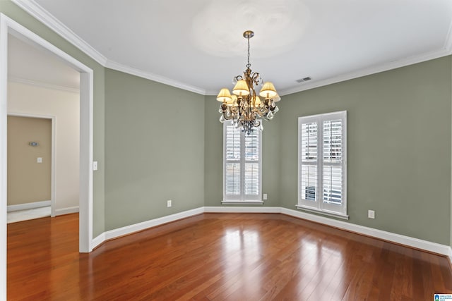 spare room featuring ornamental molding, hardwood / wood-style floors, and an inviting chandelier