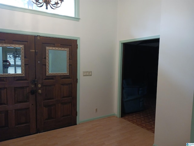 foyer with light wood-type flooring, french doors, and a chandelier