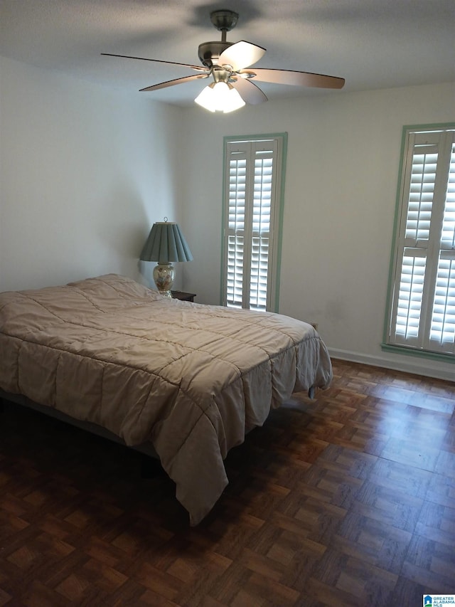 bedroom with multiple windows, ceiling fan, and dark parquet flooring