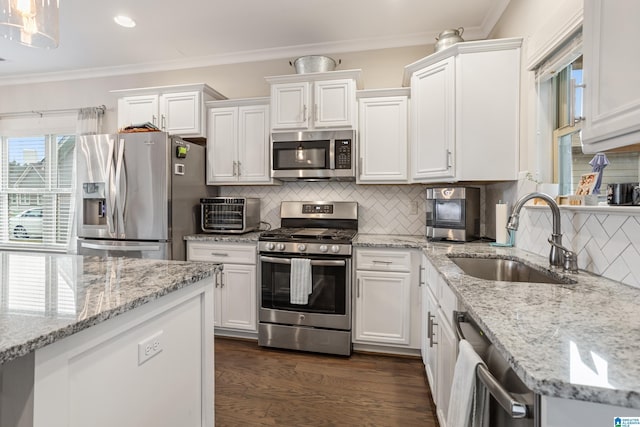 kitchen with sink, white cabinets, ornamental molding, stainless steel appliances, and light stone countertops