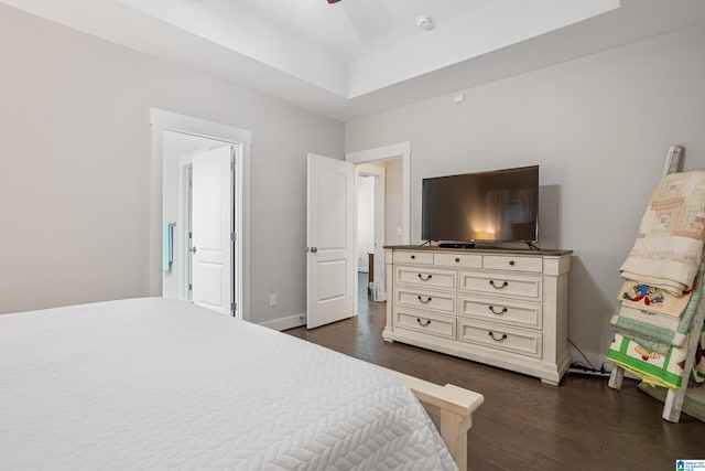 bedroom with dark wood-type flooring and a tray ceiling