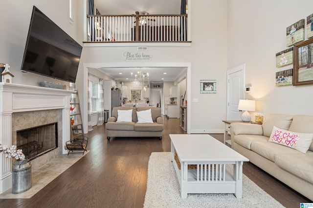 living room with a high ceiling, dark hardwood / wood-style floors, a notable chandelier, and a high end fireplace