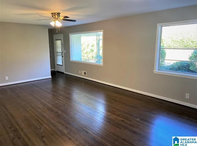 spare room featuring ceiling fan, a healthy amount of sunlight, and dark hardwood / wood-style floors