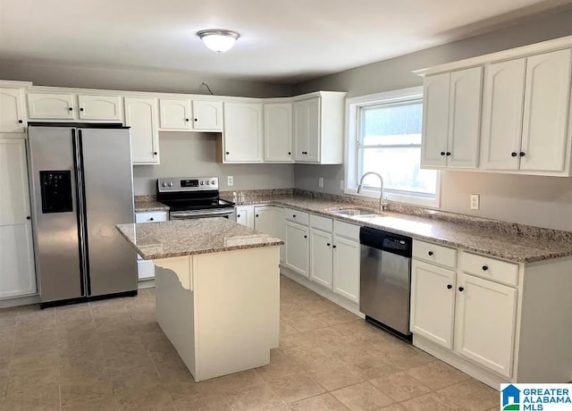 kitchen with light stone counters, appliances with stainless steel finishes, a center island, and sink