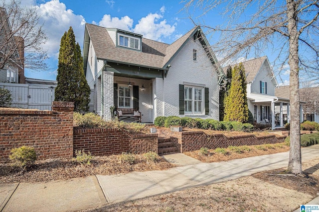 view of front of property featuring a shingled roof and brick siding