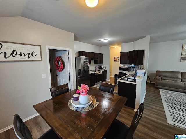 dining space featuring dark wood-type flooring and vaulted ceiling