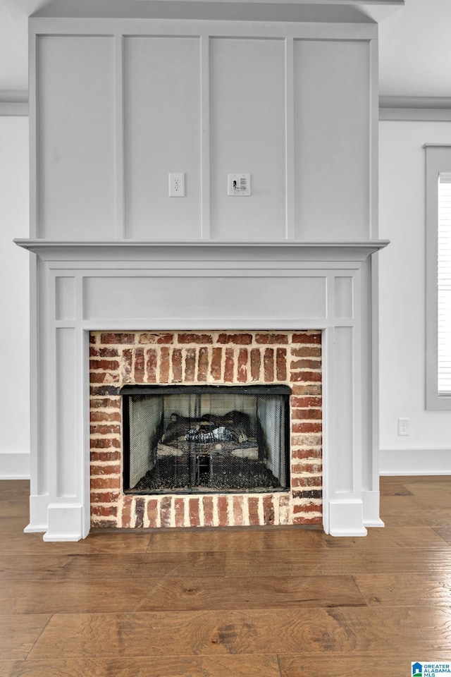 interior details with wood-type flooring and a brick fireplace