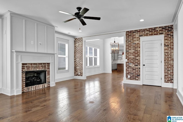 unfurnished living room with brick wall, dark wood-type flooring, and a fireplace