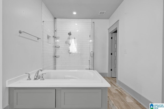 bathroom featuring independent shower and bath and wood-type flooring