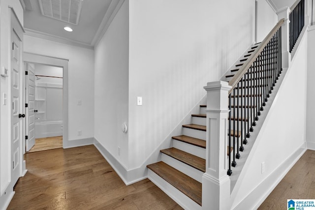 staircase featuring crown molding and hardwood / wood-style flooring