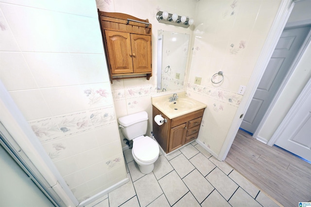 bathroom with tile patterned floors, vanity, toilet, and tile walls