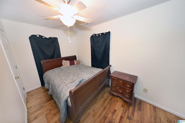 bedroom featuring ceiling fan, light hardwood / wood-style flooring, and a textured ceiling