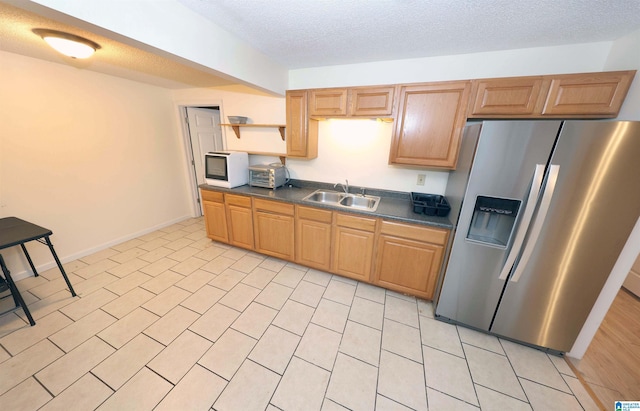 kitchen featuring stainless steel refrigerator with ice dispenser, sink, and a textured ceiling