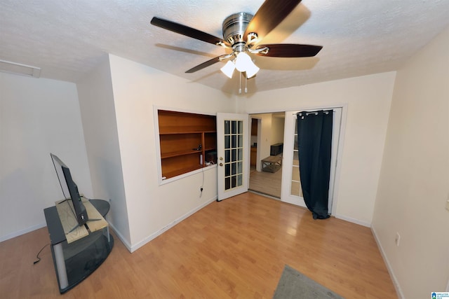 empty room featuring ceiling fan, light hardwood / wood-style floors, french doors, and a textured ceiling