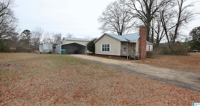 view of front of property featuring a carport, a front yard, and a storage shed