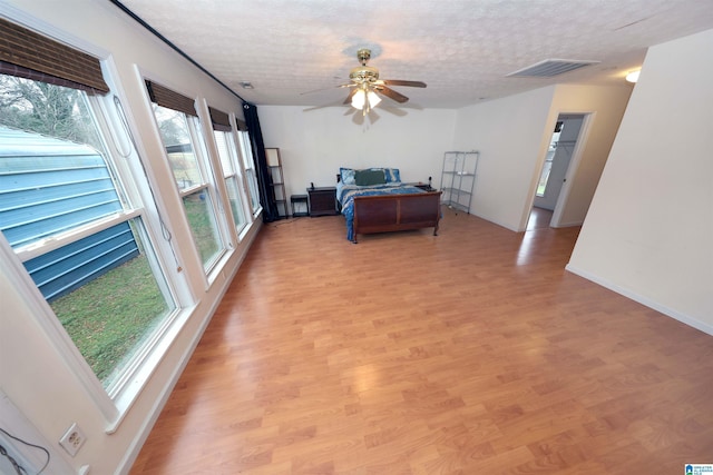 bedroom with ceiling fan, a textured ceiling, and light hardwood / wood-style flooring