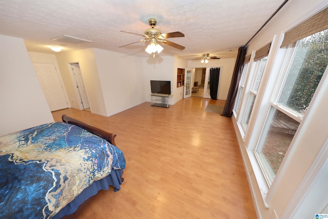 bedroom featuring ceiling fan, wood-type flooring, and a textured ceiling