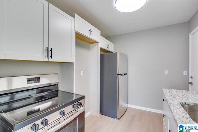 kitchen featuring light stone counters, stainless steel appliances, white cabinets, and light wood-type flooring