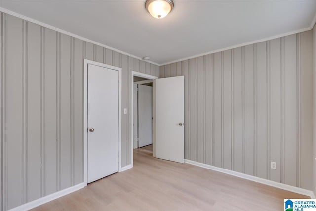 unfurnished bedroom featuring crown molding and light wood-type flooring