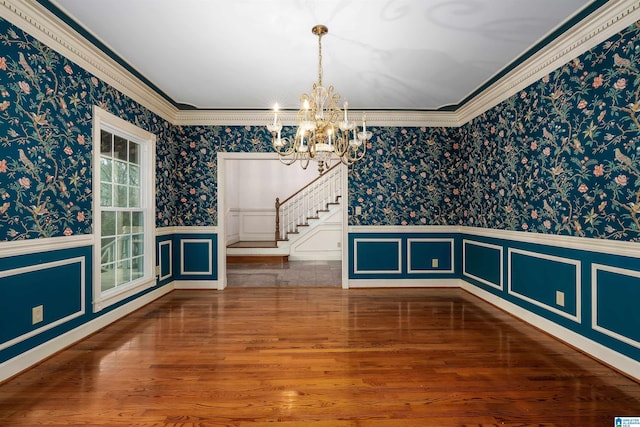 unfurnished dining area featuring an inviting chandelier, hardwood / wood-style flooring, and ornamental molding